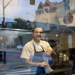 Sadr smiling behind the window of the restaurant